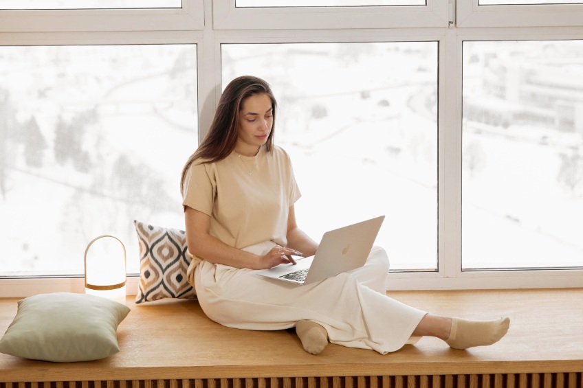 woman sitting in front of window with laptop